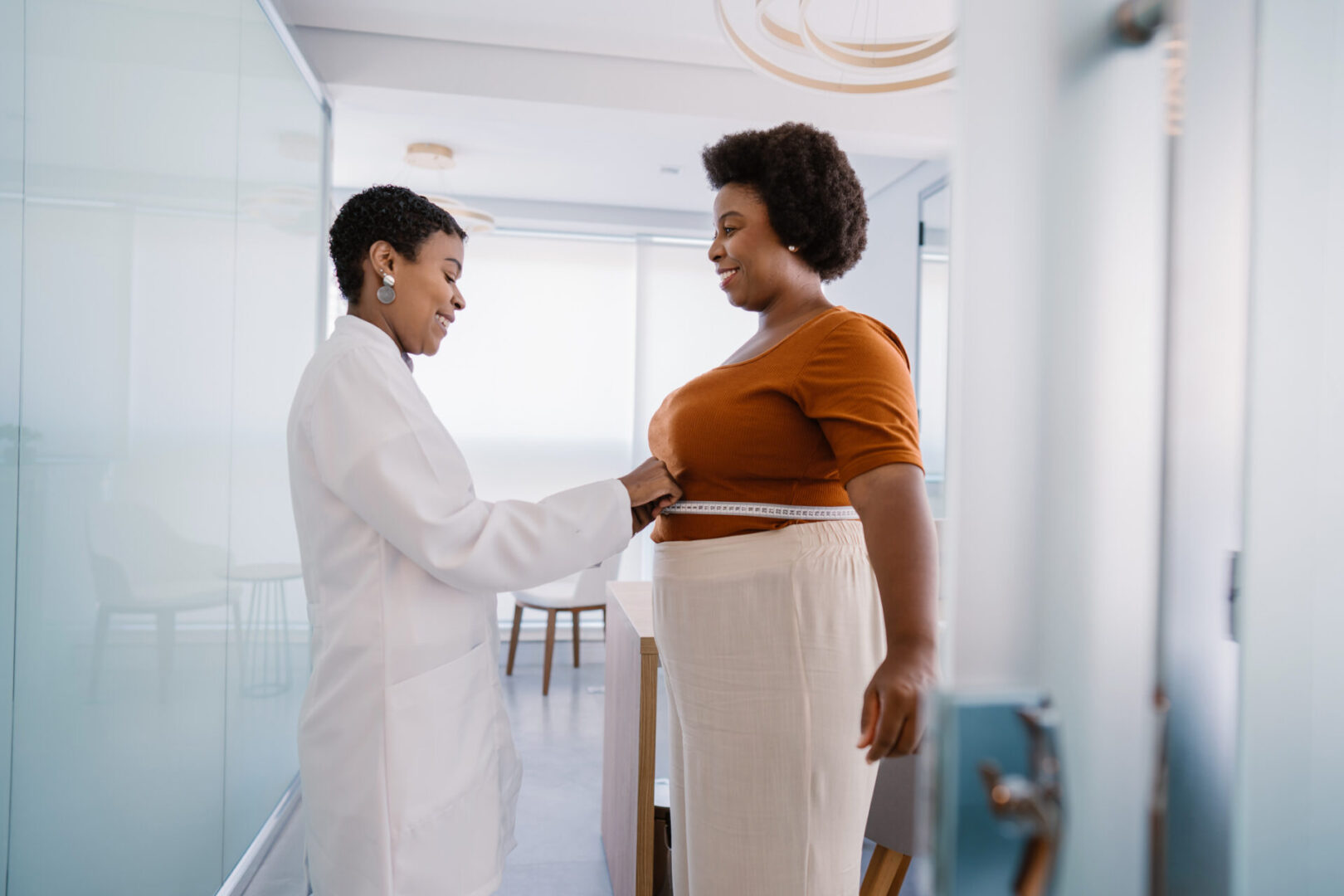 Doctor measuring pregnant woman's belly during checkup.