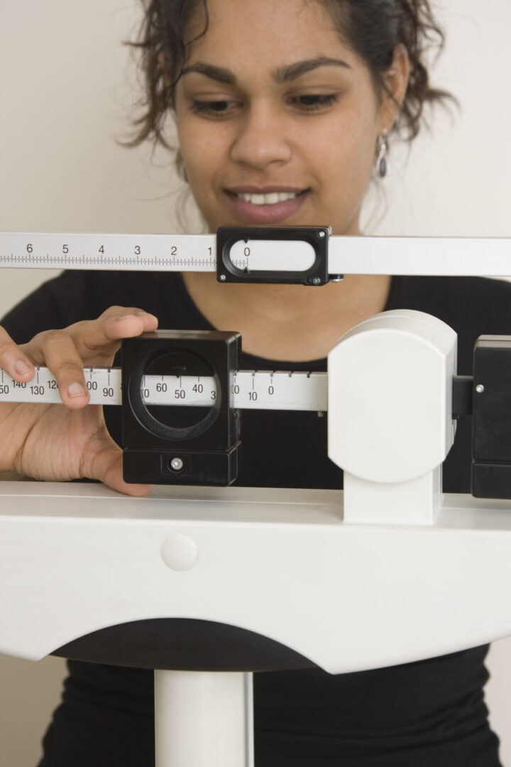 A person adjusting a camera focus scale with a ruler.